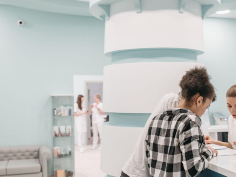 A imagem mostra o ambiente de recepção e atendimento de uma clínica médica, hospital ou centro de estética moderno e bem estruturado.