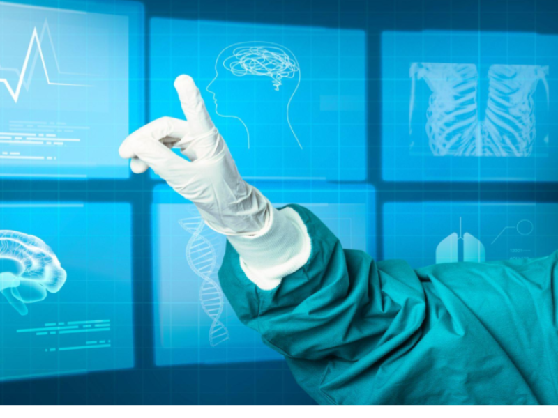 A imagem mostra uma mão usando uma luva médica branca, vestindo um avental cirúrgico verde, apontando para uma interface digital futurista projetada como uma tela virtual azul.