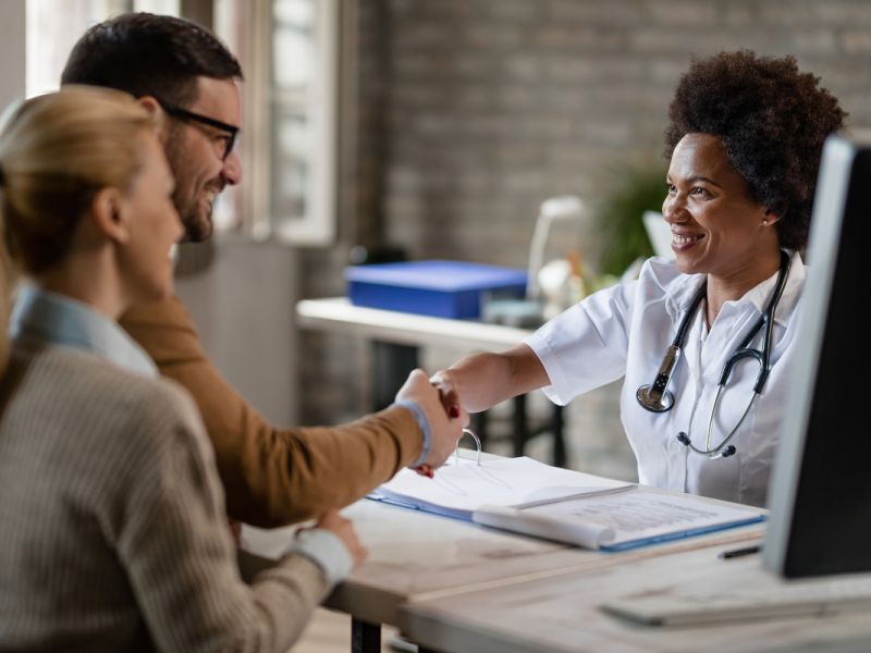 A imagem captura um momento de interação cordial e profissional em um ambiente que parece ser um consultório médico.