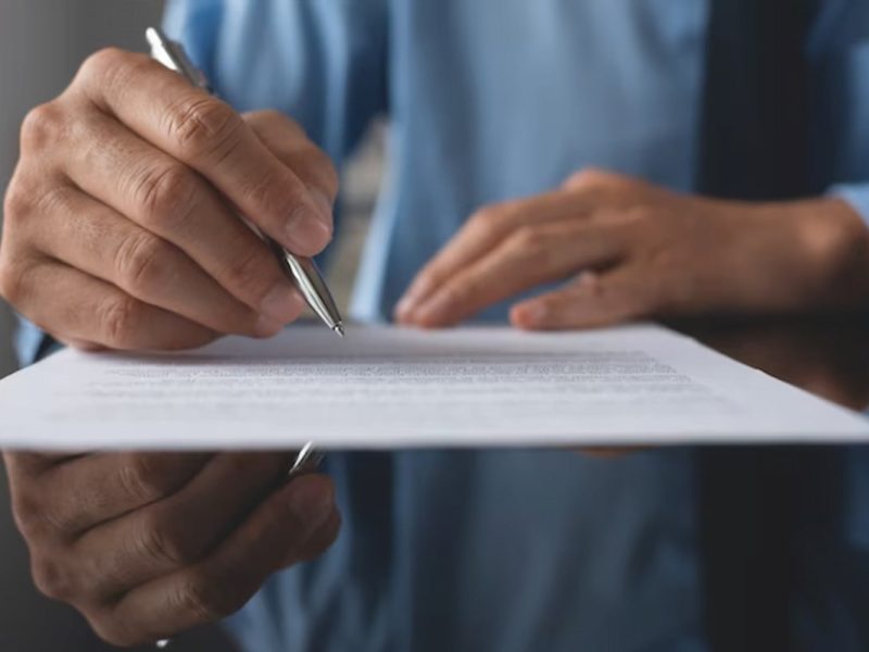 Homem de terno assinando o atestado de comparecimento médico.