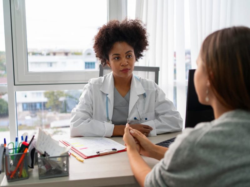 Médica em consulta, ouvindo atentamente uma paciente, mostrando uma estratégia para atrair pacientes particulares com atendimento humanizado.