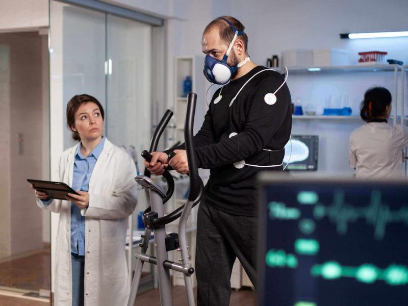 Um médico realizando uma avaliação médica em um paciente usando equipamento de reabilitação.