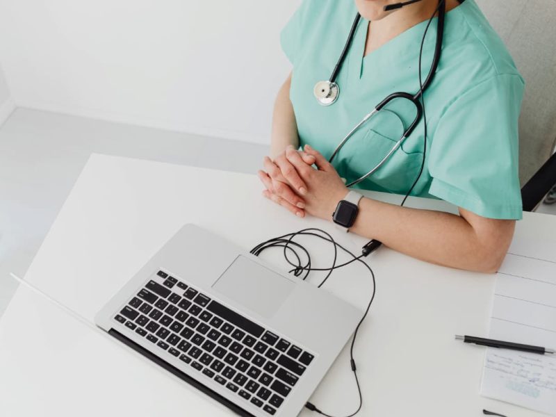 Profissional da saúde usando o laptop, representando os benefícios da prescrição digital.