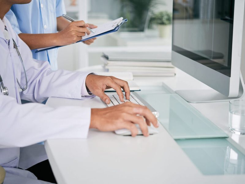 Médicos de jaleco branco trabalhando nos computadores da na central de laudos médicos da clínica
