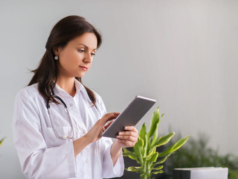 Uma médica de jaleco branco vê o que mudou na classificação de doenças com o cid-11 usando um tablet