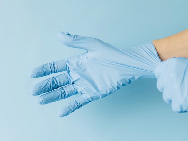 Médico usando luvas, representando uma clínica sustentável.