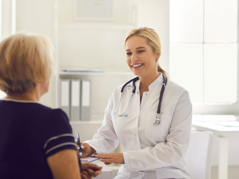 Médica sorridente com paciente, simbolizando como captar pacientes para a clínica.