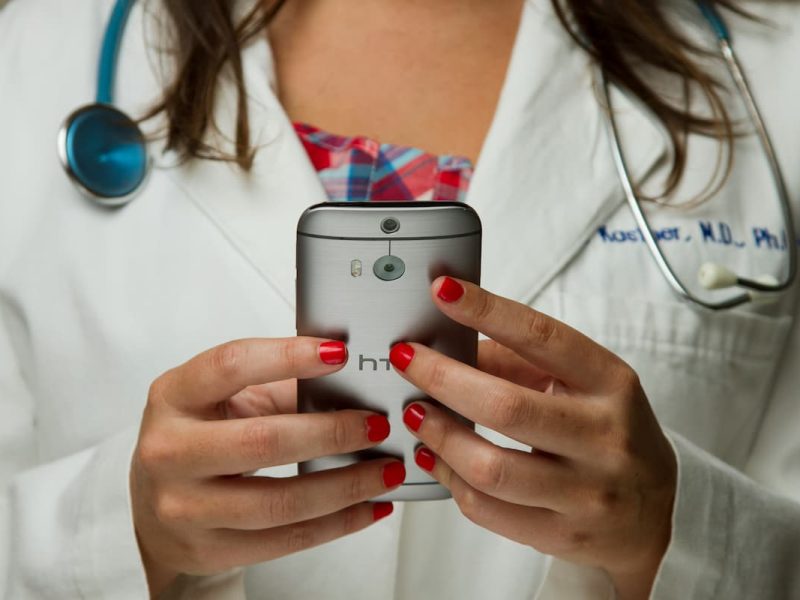 Fotografia de uma médica utilizando o celular.