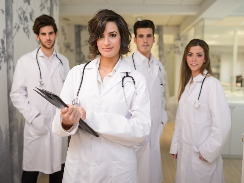 Profissionais da saúde reunidos com uma médica na frente, simbolizando como liderar uma equipe médica.
