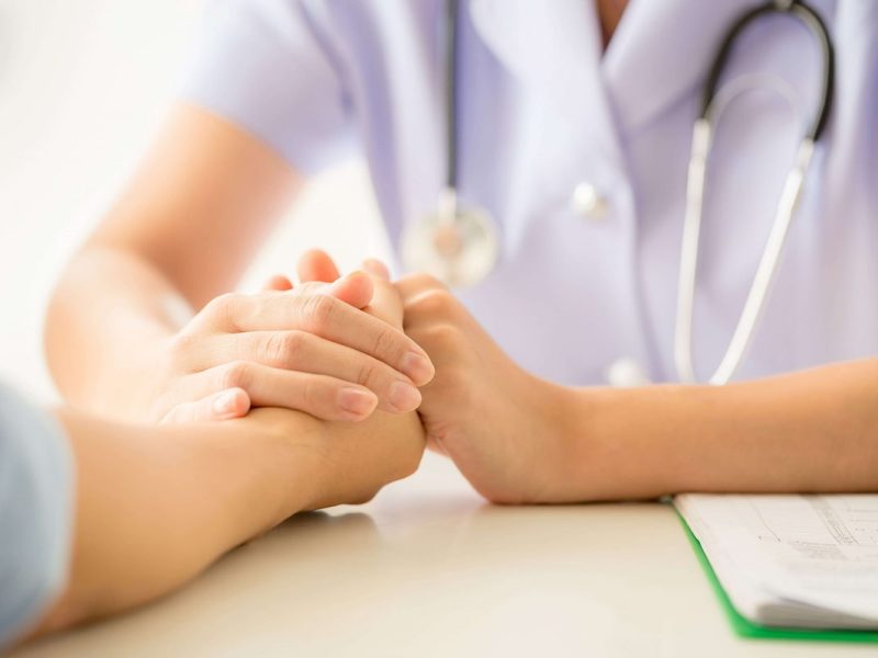 Médico segurando a mão de um paciente, exemplificando como ter um pós-consulta satisfatório com seus pacientes.