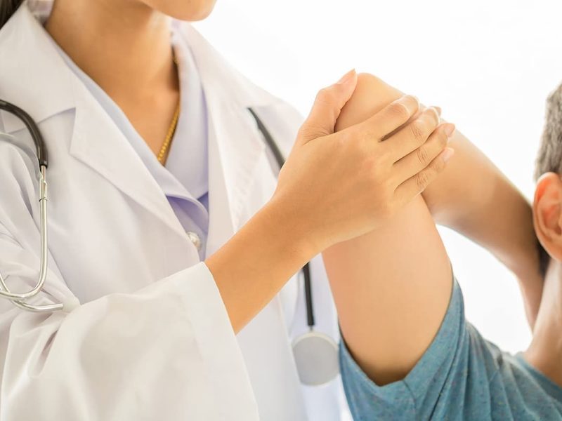 Médica tratando paciente em consultório de fisioterapia.