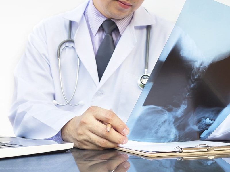 Médico examinando um exame de raio-x no consultório de ortopedia;