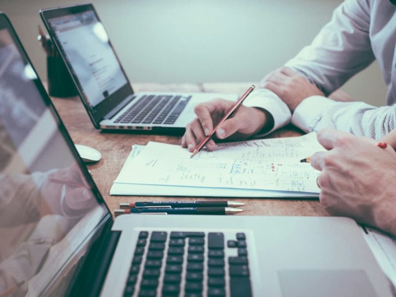 Fotografia de dois homens trabalhando em um documento de controle financeiro.