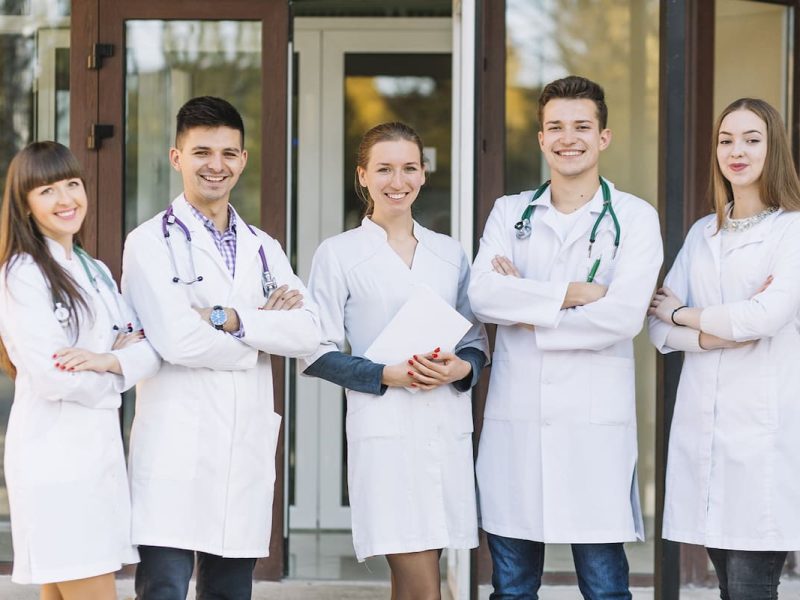 Cinco profissionais da saúde juntos , simulando um coworking para médicos.