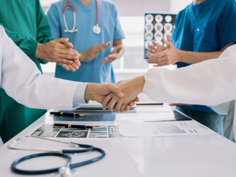 Médicos dando as mãos, representando o credenciamento médico.