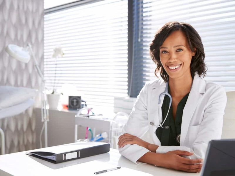 Médico em frente ao laptop para analisar as diferenças entre consultório, clínica e centro médico.