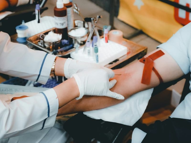 profissional da saúde retirando sangue de uma paciente para a realização do exame.