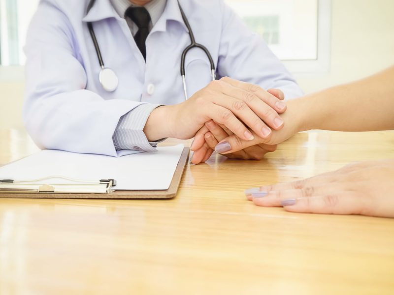 Profissional da saúde segurando a mão de paciente para melhorar a experiência do paciente com a medicina.