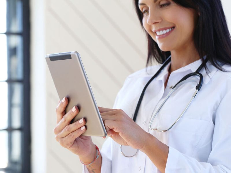uma médica de jaleco branco, com estetoscópio e um tablet faz um facebook ads para medicos