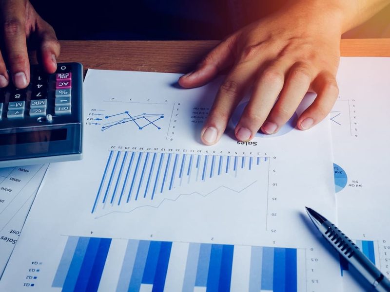 Médico analisando dados em papel com calculadora, representando a gestão financeira para clínicas.