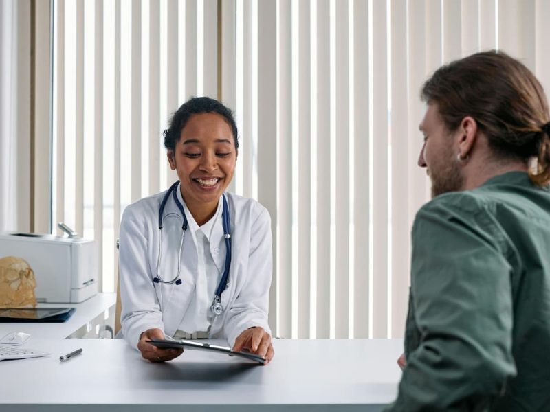 Fotografia de uma médica que atende um paciente de acordo com os princípios da Interoperabilidade na saúde.