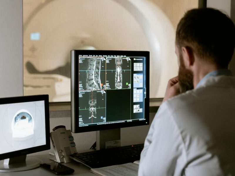 Fotografia de um médico que utiliza IoT durante um exame, através de seu computador.