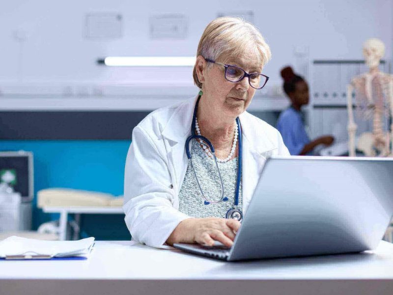 Médico usando laptop para trabalhar em saúde, destacando o papel do IoT na saúde.