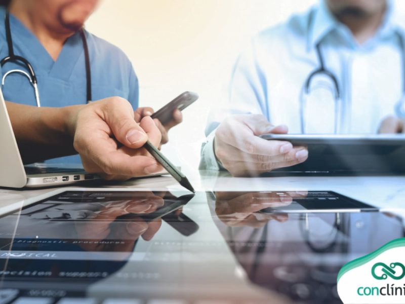 Profissionais de saúde analisando laudo de exame em um tablet digital em ambiente clínico.