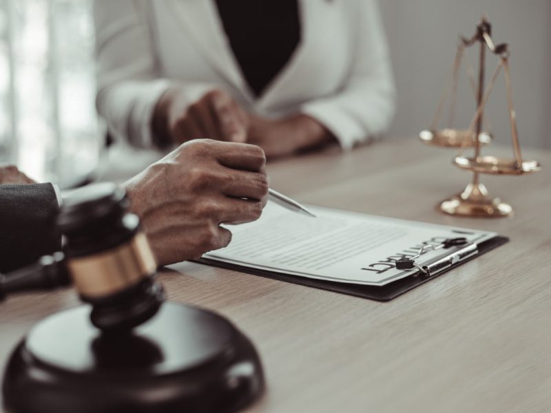 Assinatura de contrato seguindo a lei do plano de saúde, com balança e martelo jurídico ao fundo.
