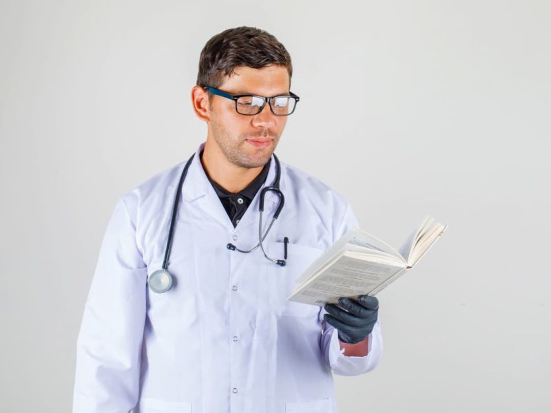 Imagem de um médico lendo um livro, destacando a importância de livros para médicos na formação e atualização profissional.