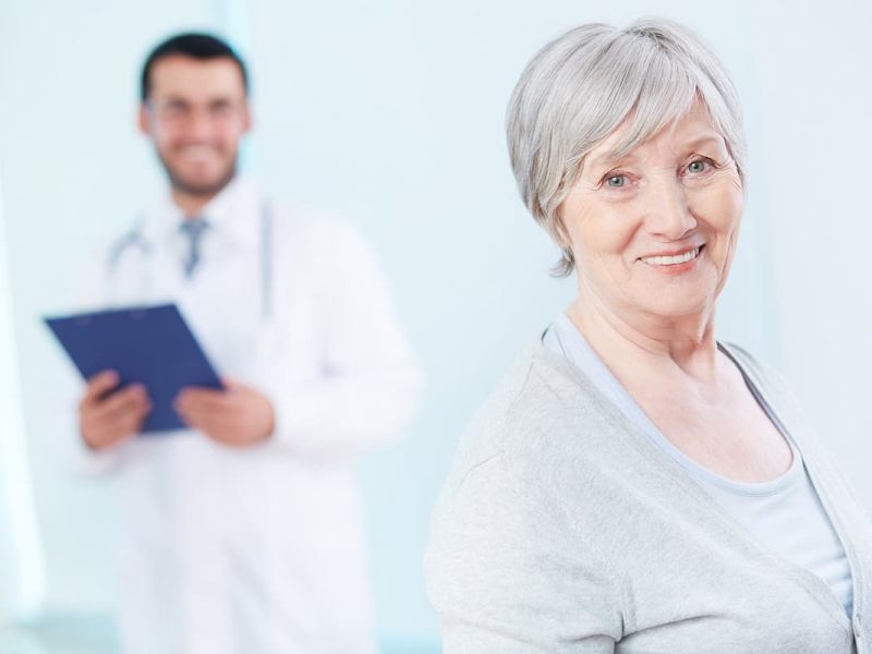 Médico e paciente idosa sorrindo, representando o marketing para clínica de geriatria.