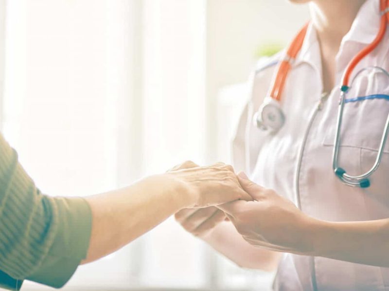 Profissional da saúde segurando a mão do paciente, representando os benefícios da medicina integrativa.