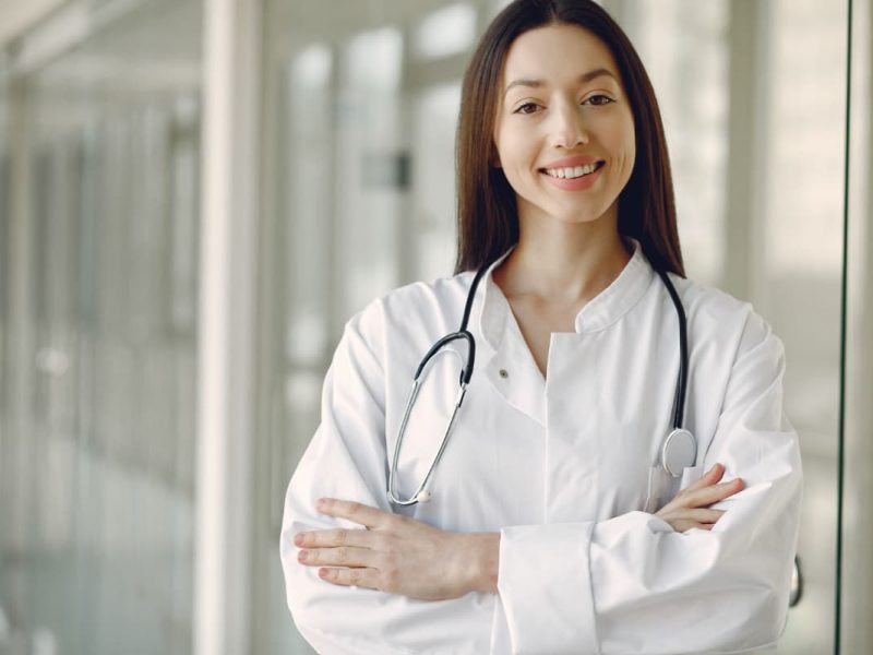 Médica cruzando os braços com um sorriso no rosto, simbolizando a experiência de médico empreendedor.