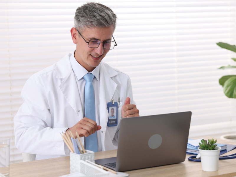 medico olhando para o laptop e sorrindo