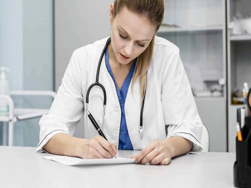 médica de jaleco branco preenchendo um modelo de termo de consentimento livre e esclarecido