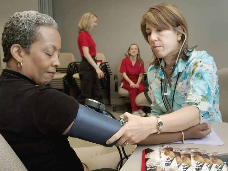 Médica medindo pressão de pessoas em uma empresa.