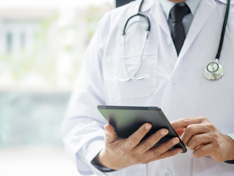 Médico usando o tablet digital para aplicar o Princípio de Pareto na clínica médica.