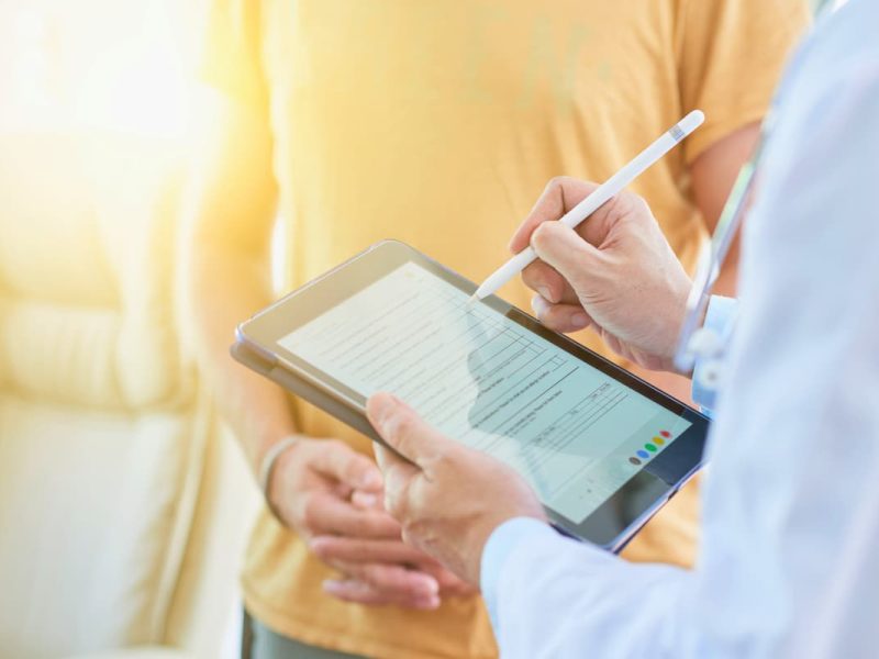 Médico preenche prontuário eletrônico do paciente em um tablet, representando as vantagens e desvantagens dessa tecnologia.