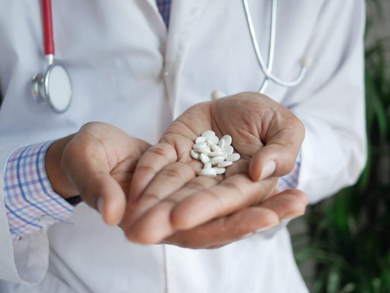 Receita de remédio: médico segurando comprimidos medicamentosos em suas mãos.