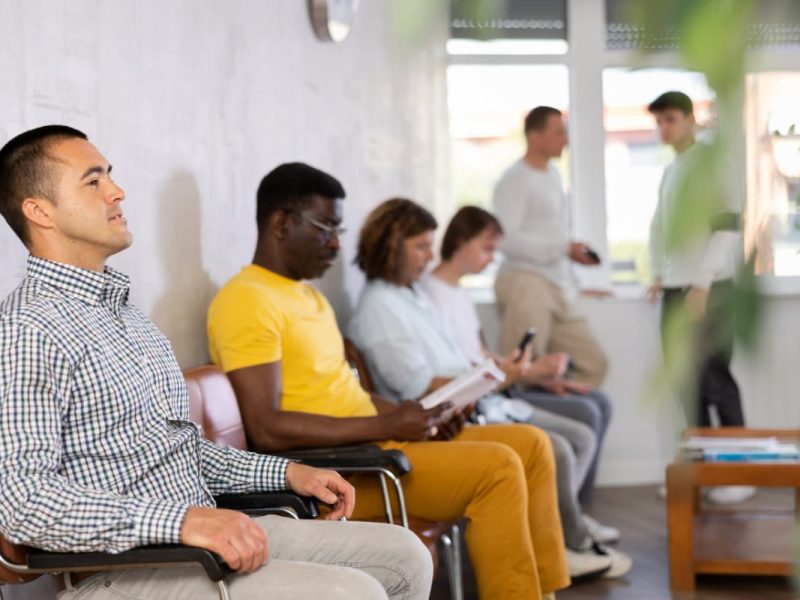 Pessoas aguardando em uma sala de espera de clínica, representando estratégias para reduzir o tempo de espera melhoram o conforto e a satisfação dos pacientes.