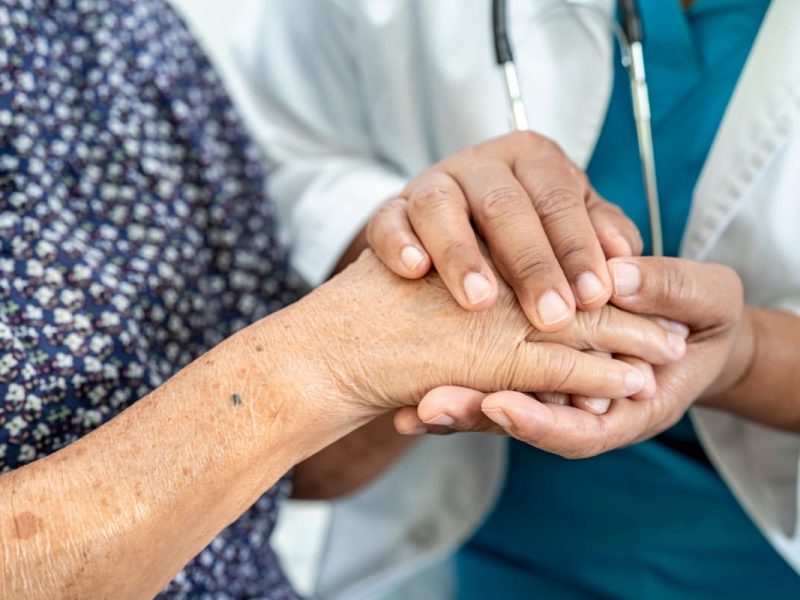 Médico segurando a mão de paciente, simbolizando uma boa relação médico-paciente.