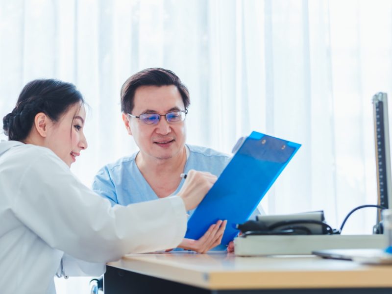 Médica mostrando relatório de paciente em uma prancheta azul.
