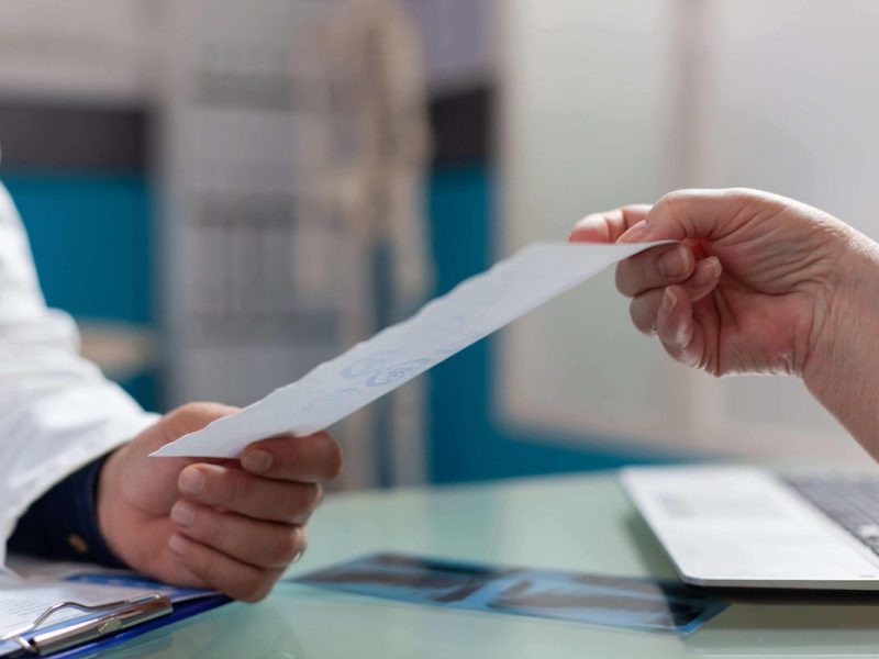 Médico entregando um relatório médico a um paciente em um consultório.