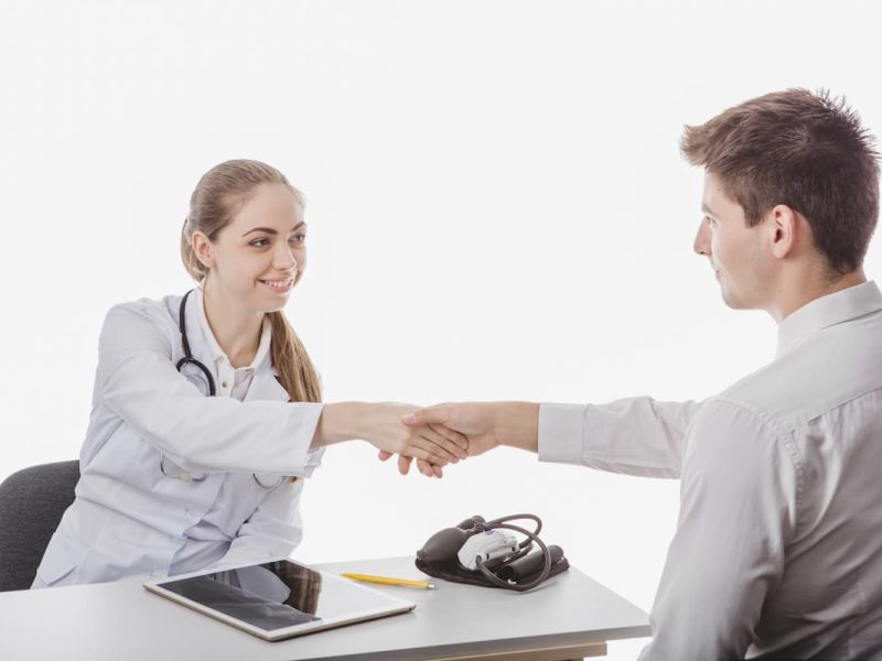 Médica cumprimentando um representante farmacêutico com um aperto de mão.