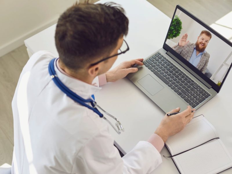 Médico verificando os resultados de exames online com paciente em teleconsulta.