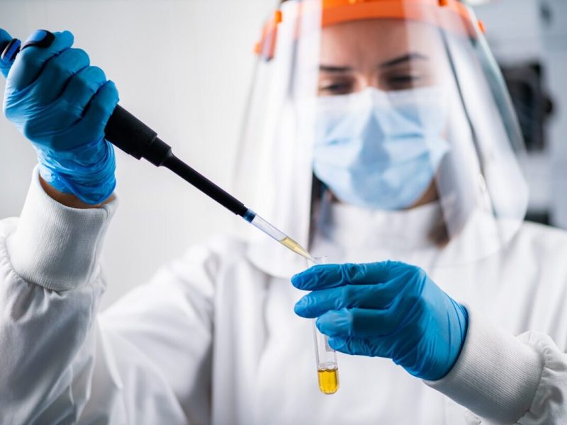 Médica manuseando material biológico e utilizando equipamentos para evitar risco biológico