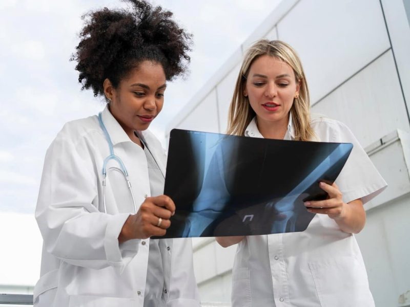 Médicas analisando riscos operacionais na radiologia no exame de radiografia em mãos.