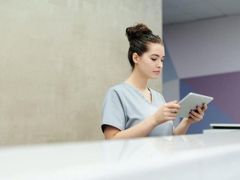 Profissional de saúde consulta sistemas de informação médica em tablet digital.