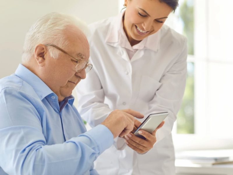 Médica demonstrando um celular com SMS para clínicas para o paciente.