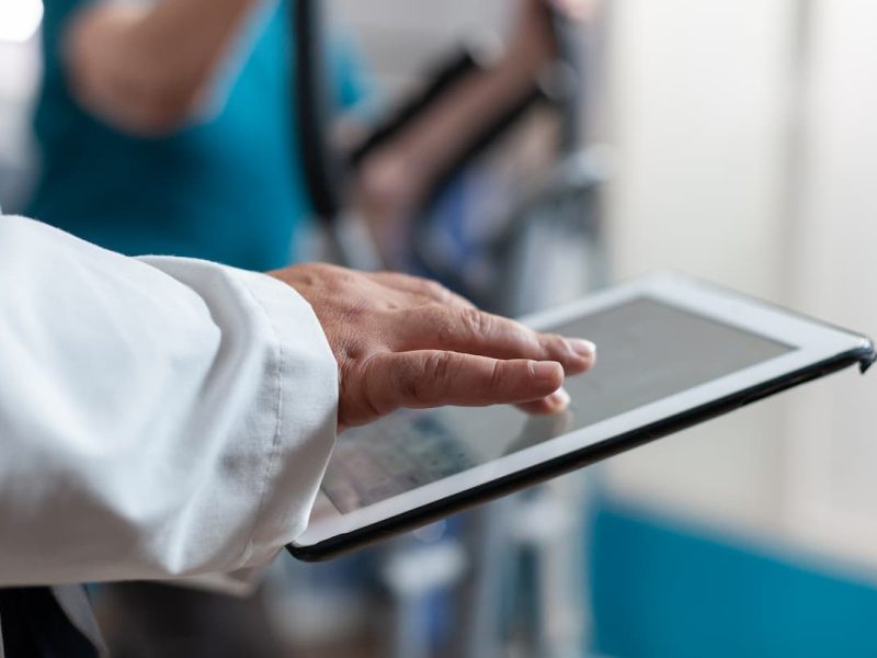 Médico usando um tablet para gestão financeira com software para fluxo de caixa de clínicas, otimizando processos administrativos.
